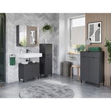Moderne Badezimmerkommode in dunklem Design, frontal fotografiert, umgeben von stilvoller Dekoration und grauen Fliesen.