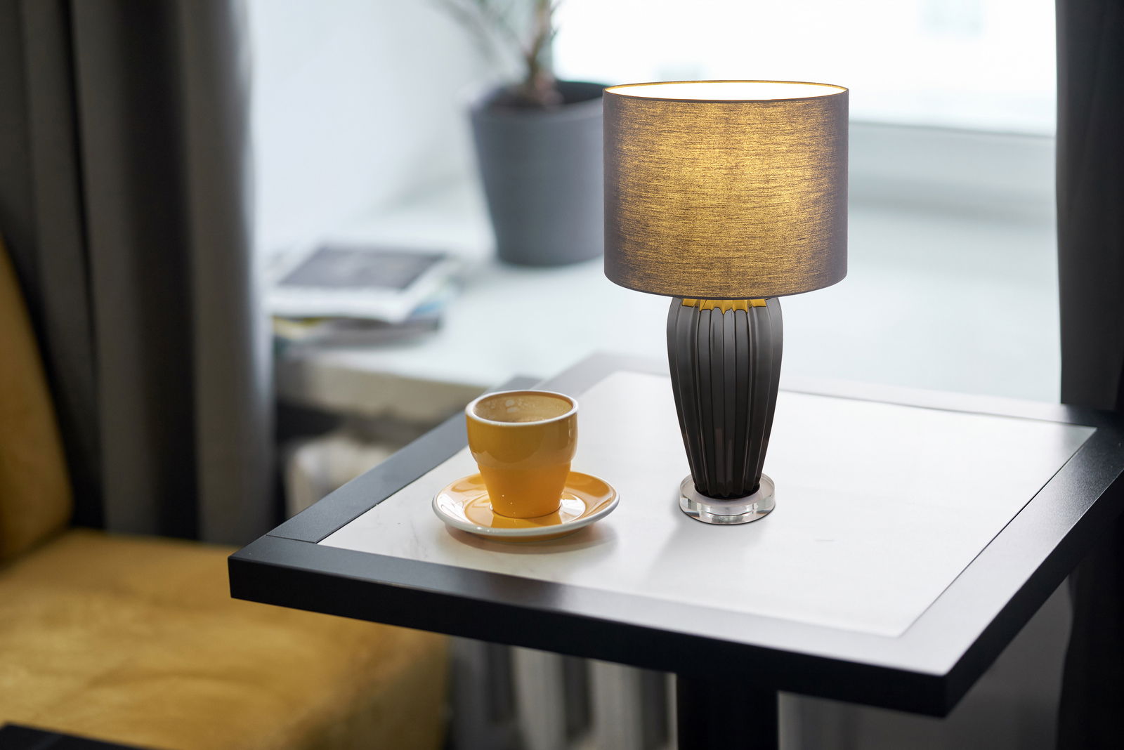 Tischleuchte IRINA von Globo Lighting auf einem Tisch neben einer Tasse Kaffee, seitliche Perspektive.