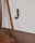 Nahaufnahme eines Garderobenhakens an einer weißen Wand, an dem eine braune Tasche hängt.