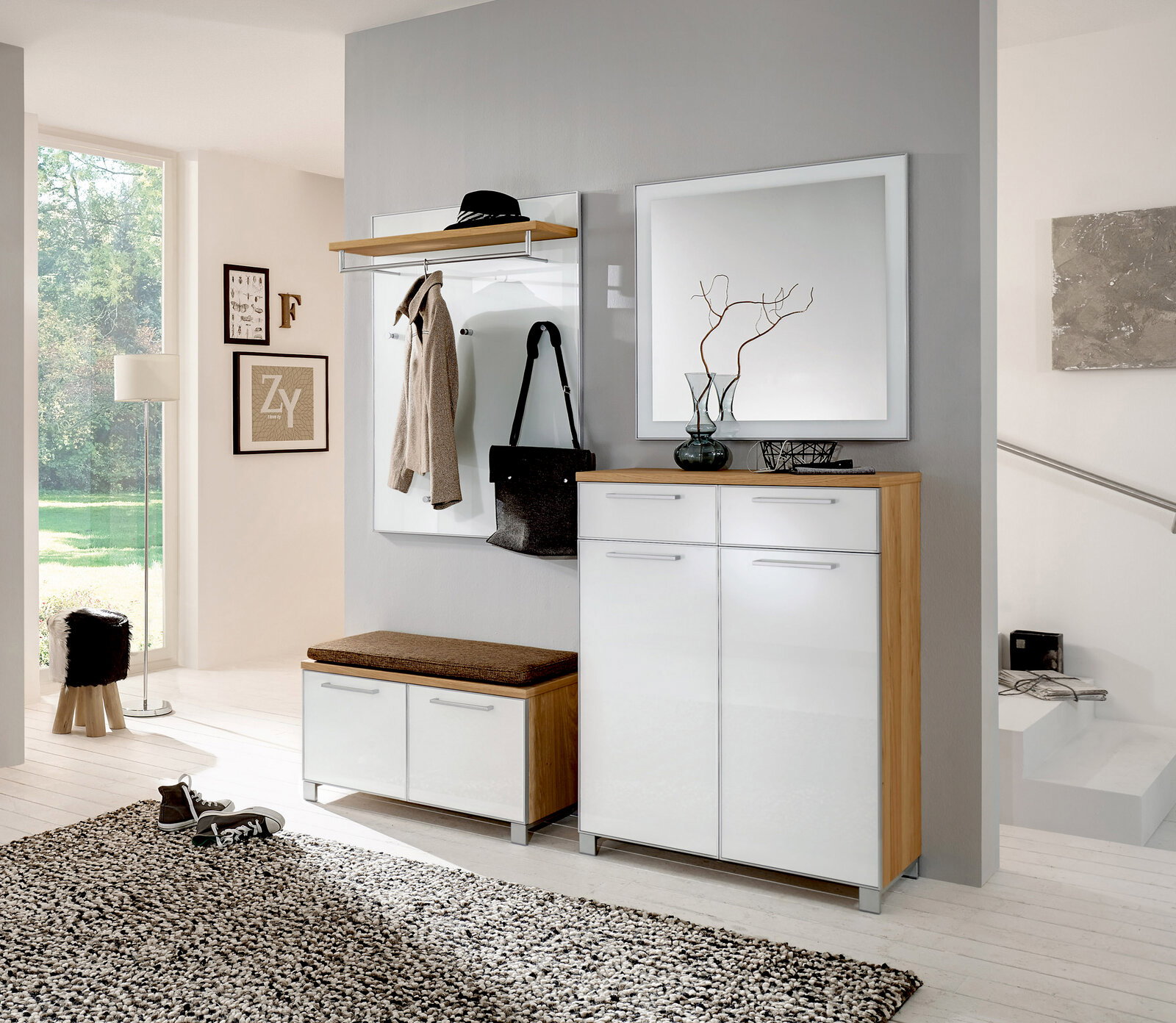 Moderne Garderobeneinrichtung mit weißem Hochglanz-Schuhschrank, Spiegel und Garderobenpaneel in einem hellen Raum. Perspektive von vorne.