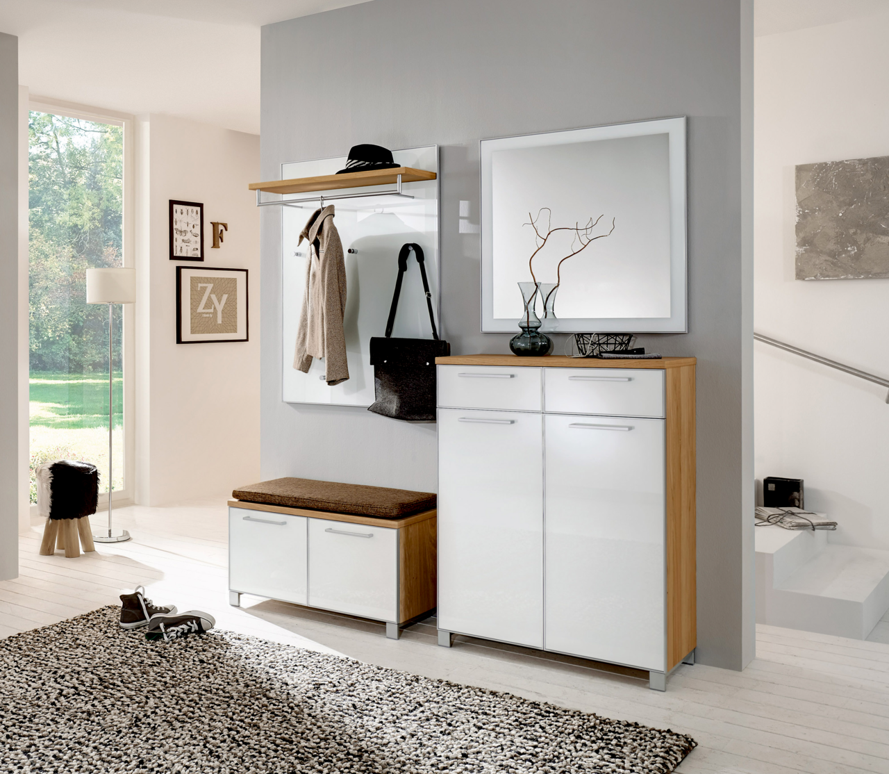 Moderne Garderobeneinrichtung mit weißem Hochglanz-Schuhschrank, Spiegel und Garderobenpaneel in einem hellen Raum. Perspektive von vorne.