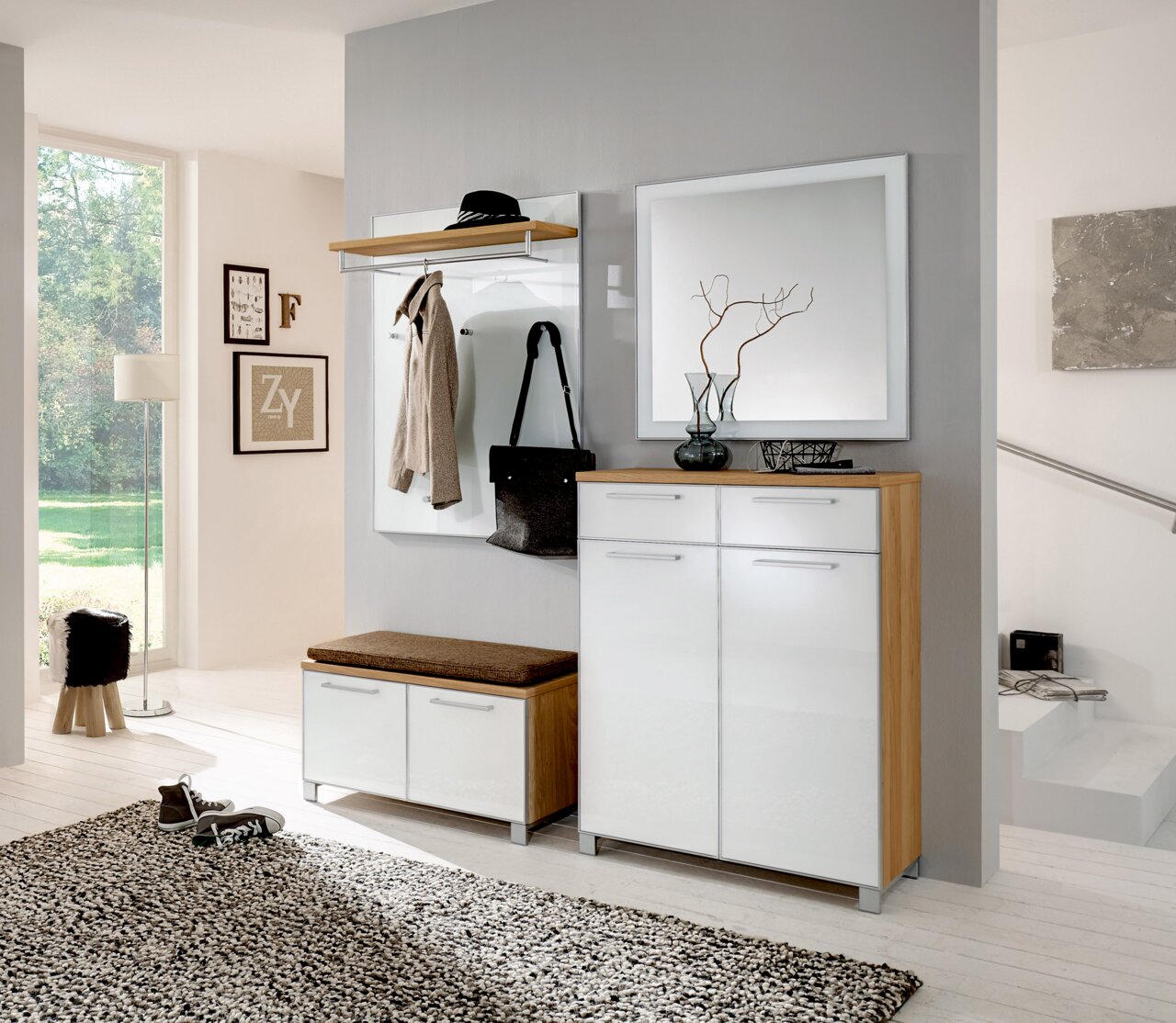 Moderne Garderobeneinrichtung mit weißem Hochglanz-Schuhschrank, Spiegel und Garderobenpaneel in einem hellen Raum. Perspektive von vorne.