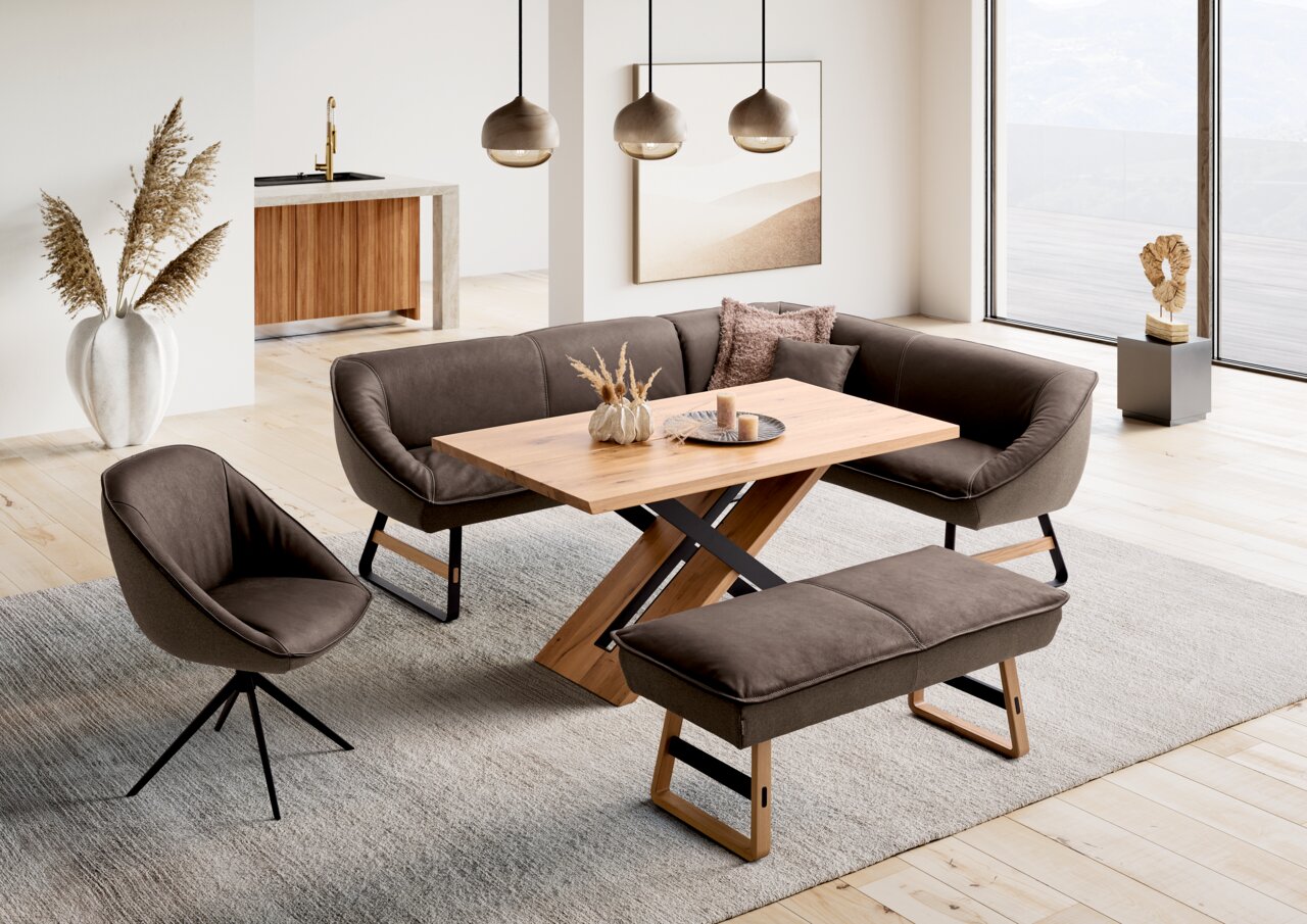 Koinor Esstisch T1617 Moderner Esstisch mit Holztischplatte und X-förmigem Gestell, umgeben von stilvollen Polstermöbeln in einem hellen, offenen Wohnraum. Perspektive von schräg oben.