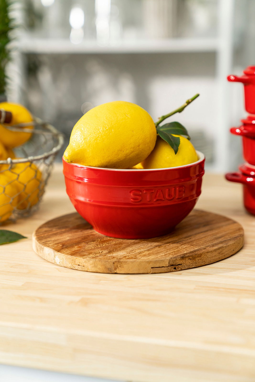 Rote Schüssel mit Zitronen auf einem Holzbrett, seitliche Perspektive