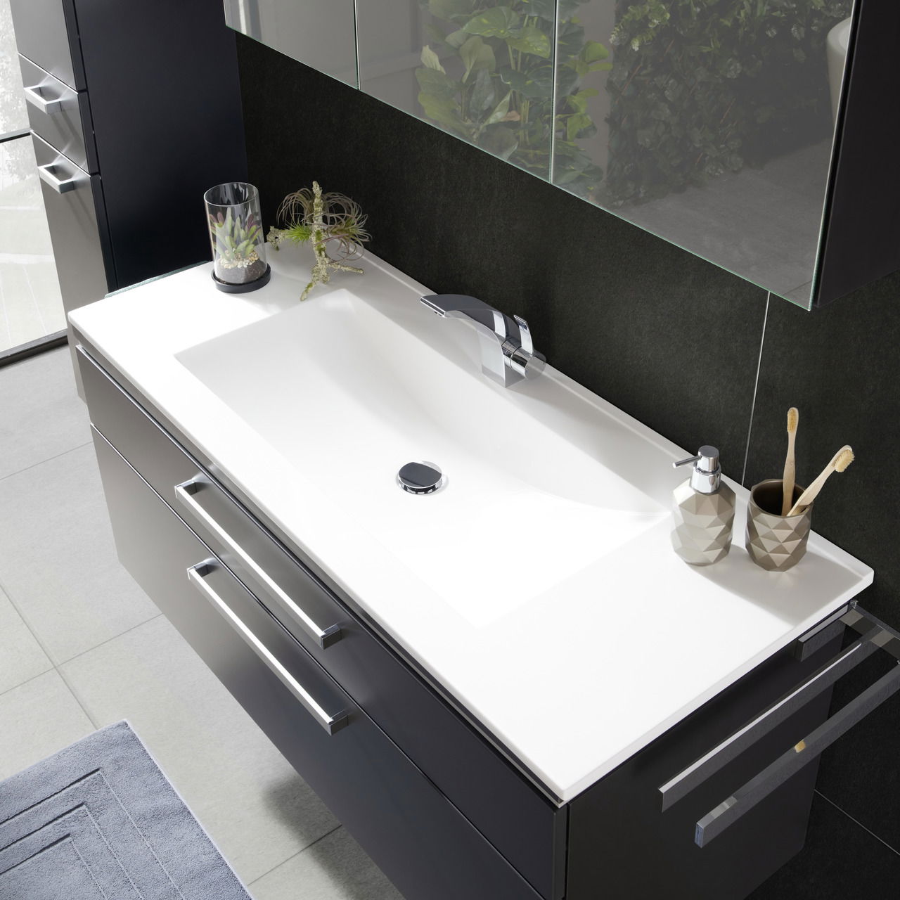 Moderne Badkombination mit weißem Waschbecken und dunklem Unterschrank, von oben betrachtet.