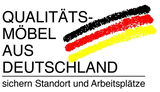 Logo mit der Aufschrift 'Qualitätsmöbel aus Deutschland' in den Farben Schwarz, Rot und Gelb, perspektivisch von vorne.