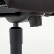 Nahaufnahme der Unterseite eines Chefsessels mit Fokus auf die Höhenverstellung.