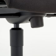 Nahaufnahme der Unterseite eines Chefsessels mit Fokus auf die Höhenverstellung.