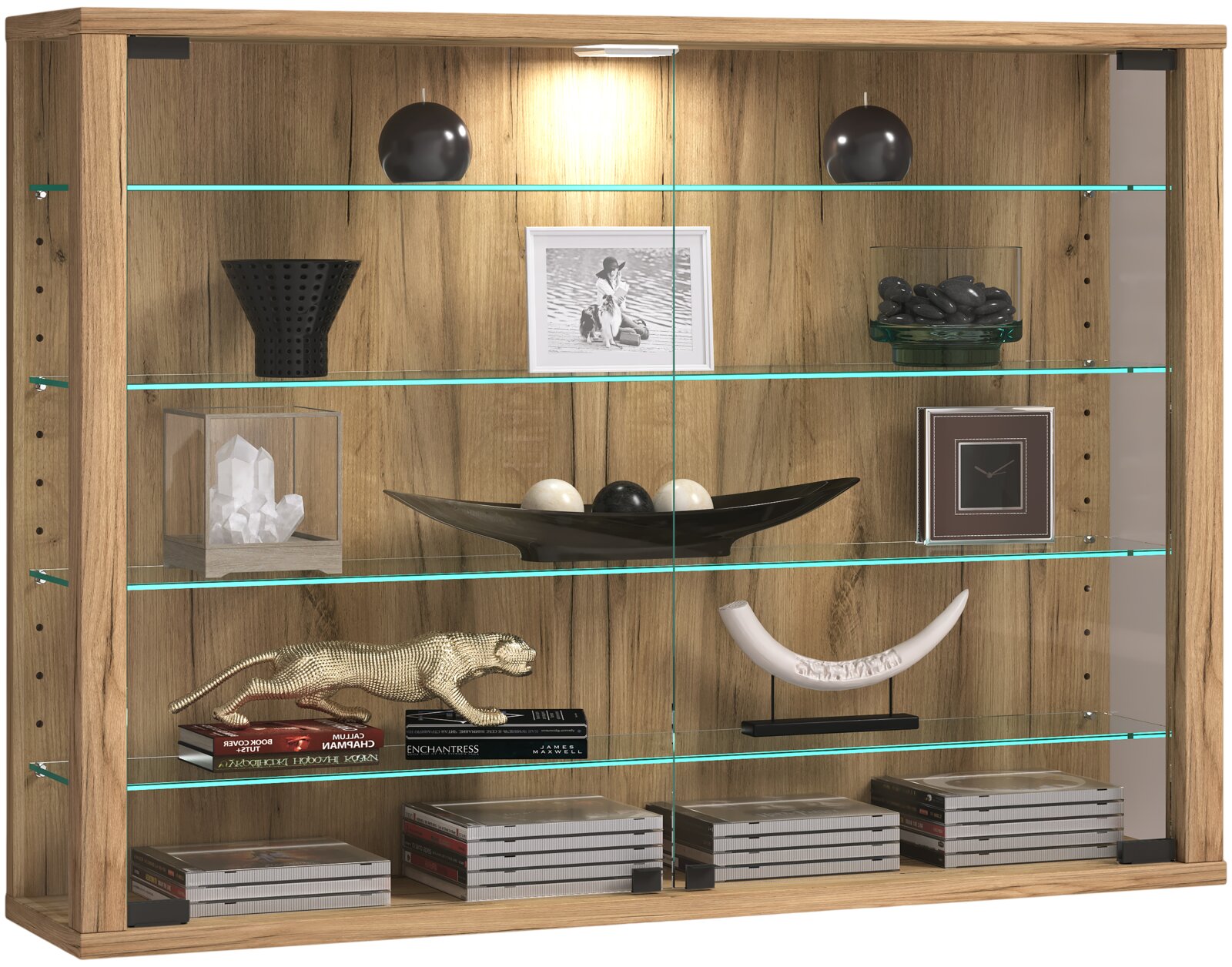Holzfarbene Vitrine mit Glasböden und integrierter Beleuchtung, dekoriert mit Schalen, Bilderrahmen und Büchern, Frontansicht.