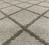 Nahaufnahme eines Stoffmusters mit grauem Rautenmuster, perspektivisch von der Seite aufgenommen.