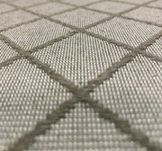 Nahaufnahme eines Stoffmusters mit grauem Rautenmuster, perspektivisch von der Seite aufgenommen.