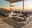Moderne Loungegarnitur auf Terrasse mit Meerblick bei Sonnenuntergang, bestehend aus einem großen Loungetisch, zwei Loungesesseln und einem Ecksofa, aus seitlicher Perspektive fotografiert.