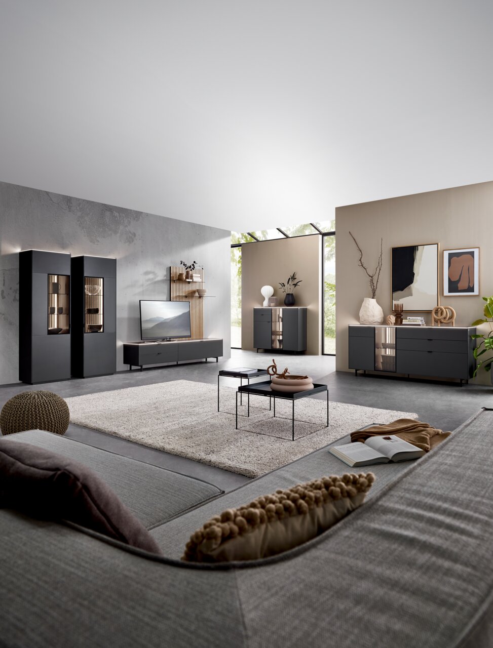 Moderne Wohnzimmermöbel in einem stilvollen Raum mit grauen Vitrinen, Sideboard und Highboard, Perspektive von der Sofaecke aus