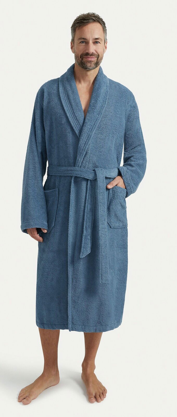 Mann in einem blauen Bademantel mit Schalkragen, stehend in Frontalansicht.