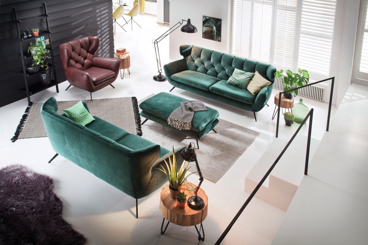 Groene tweezitsbank in een moderne woonkamer, gefotografeerd vanuit vogelperspectief.
