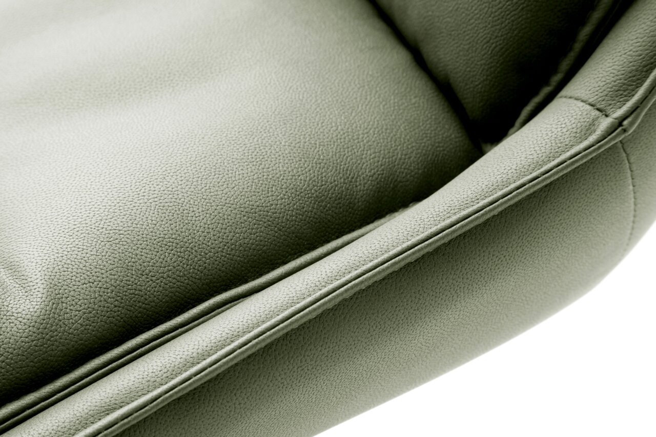 Nahaufnahme eines grünen Stuhlsitzes aus Leder, von oben betrachtet.