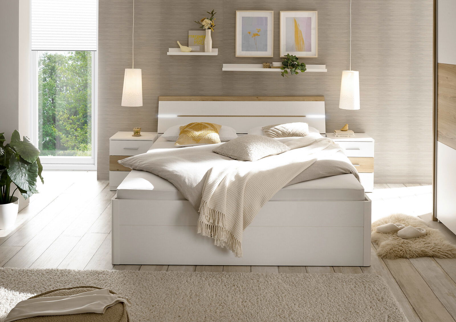 Modernes Schlafzimmer mit einem großen weißen Bett, flankiert von zwei Nachttischen. Das Bett ist mit neutralen Kissen und Decken dekoriert. Im Hintergrund sind zwei schwebende Regale mit Pflanzen und Bildern an der Wand. Die Perspektive zeigt das Schlafz