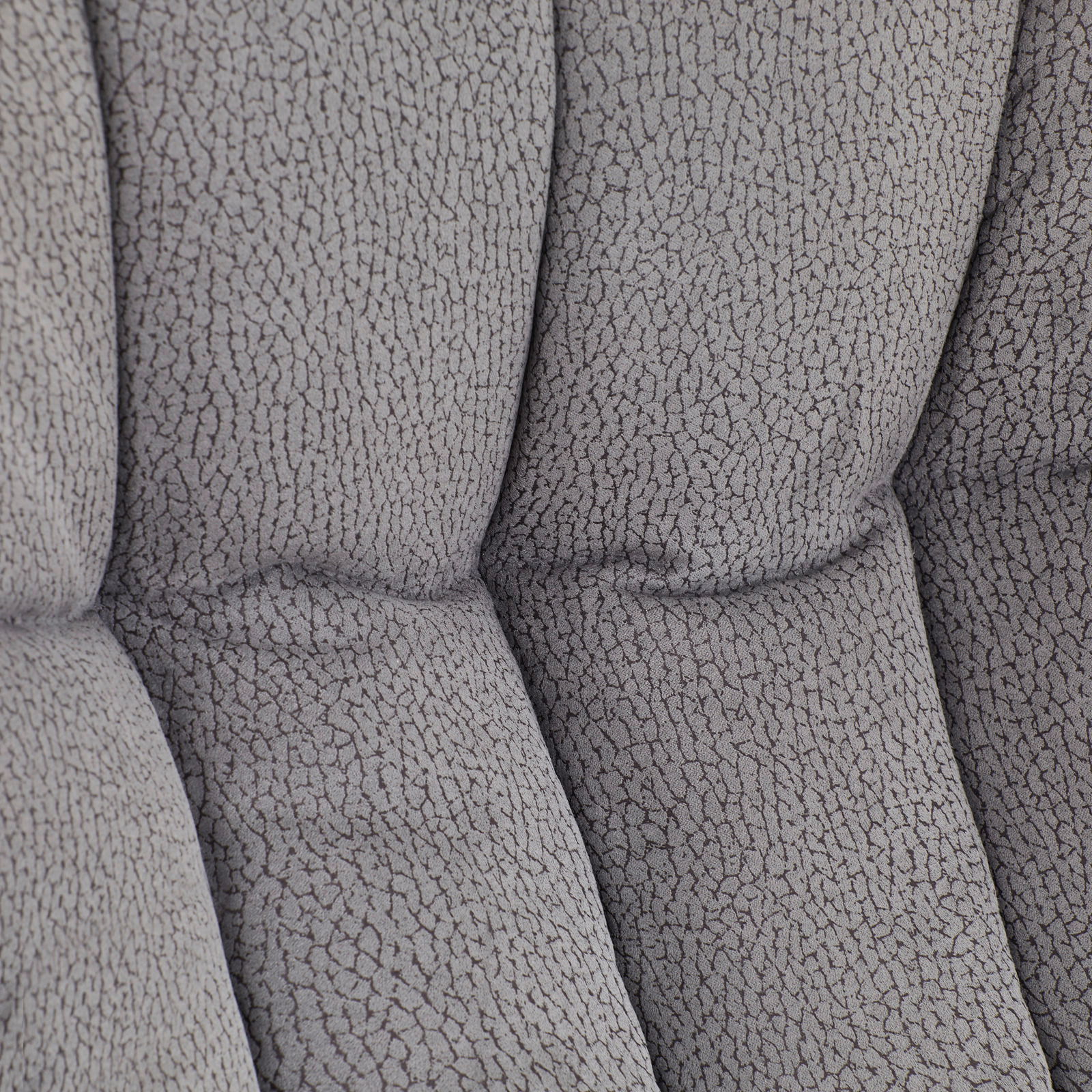 Nahaufnahme der gepolsterten Rückenlehne eines grauen Chefsessels mit strukturierter Oberfläche.