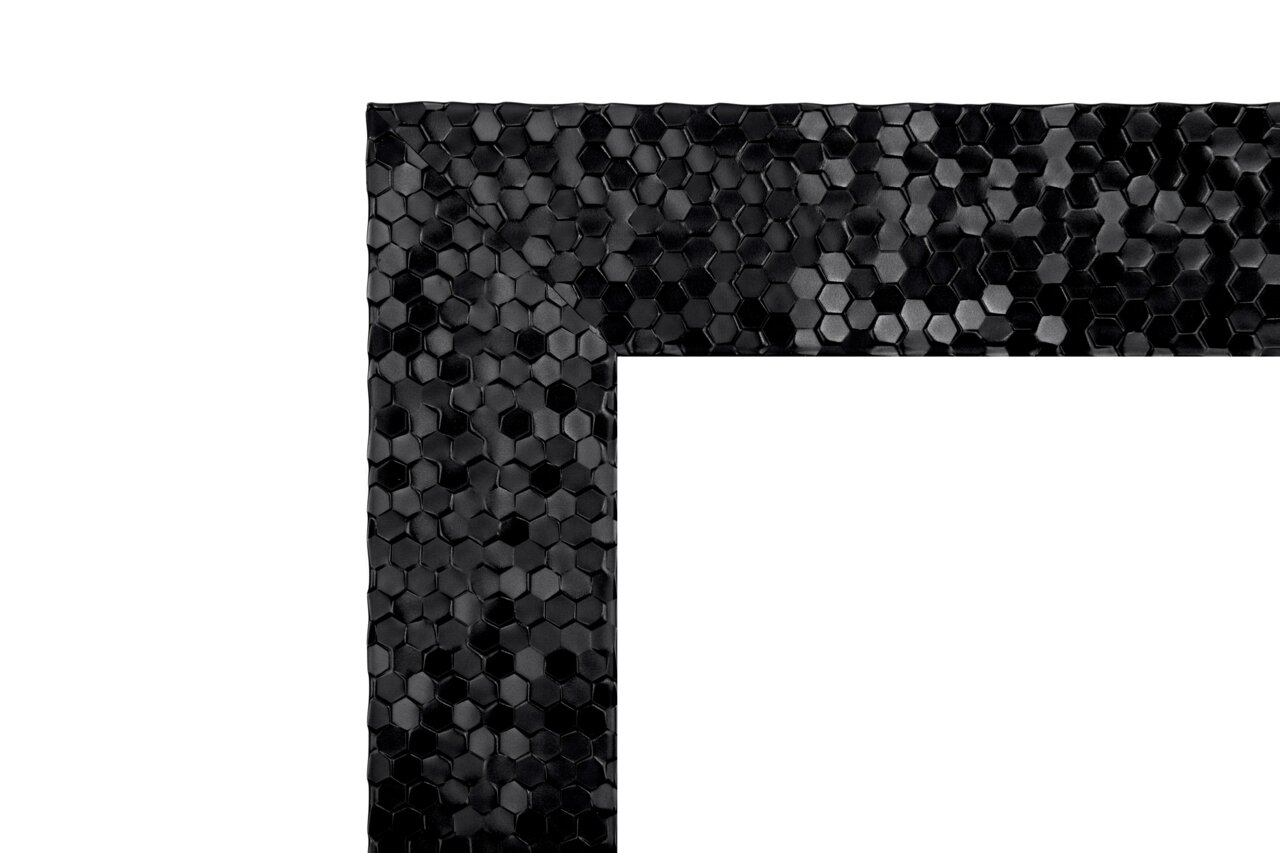 Nahaufnahme eines Spiegels mit schwarzem, sechseckigem Mosaikrahmen, Perspektive auf die Ecke des Rahmens.