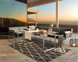 Moderner Loungetisch auf einer Terrasse mit Blick auf den Sonnenuntergang, umgeben von stilvollen Sofas und dekorativen Elementen, aus seitlicher Perspektive.