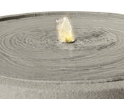 Nahaufnahme eines modernen Brunnens mit sprudelndem Wasser in der Mitte, von oben betrachtet.