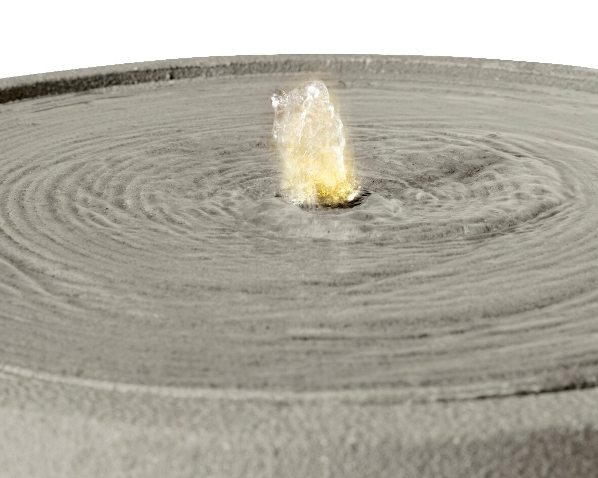 Nahaufnahme eines modernen Brunnens mit sprudelndem Wasser in der Mitte, von oben betrachtet.