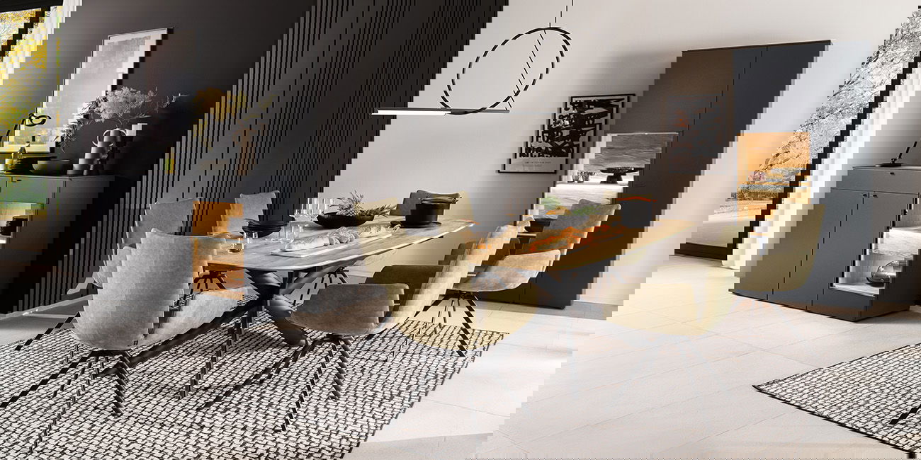 Ein elegantes Esszimmer mit Holztisch, grünen Stühlen, schwarzer Deko und moderner Beleuchtung.