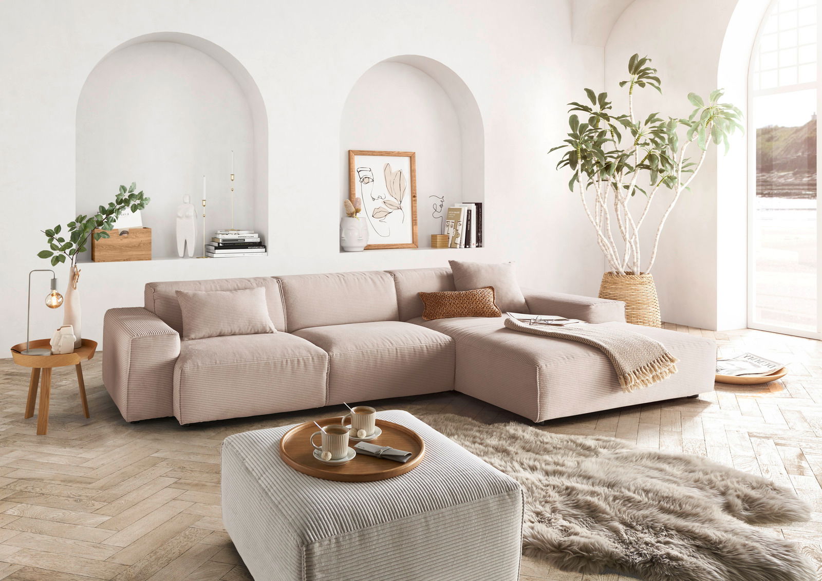 Gemütliche Rundecke in einem modernen Wohnzimmer, mit hellen Stoffen und dekorativen Kissen, aus der Perspektive von vorne rechts betrachtet.