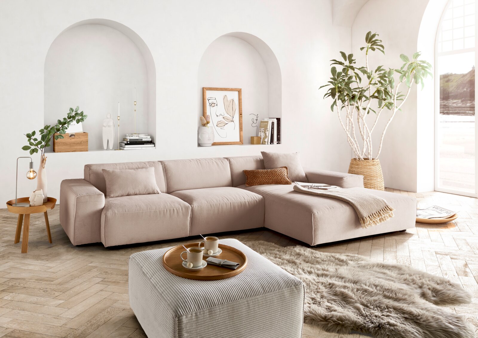 Gemütliche Rundecke in einem modernen Wohnzimmer, mit hellen Stoffen und dekorativen Kissen, aus der Perspektive von vorne rechts betrachtet.