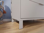 Nahaufnahme einer weißen, breiten Kommode auf Holzfußboden, seitliche Perspektive