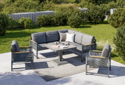Moderne Loungegarnitur im Garten mit grauen Polstern, bestehend aus einem Ecksofa, zwei Sesseln und einem Tisch, aus der Vogelperspektive fotografiert.
