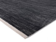 Designer Teppich in dunklen Grautönen mit heller Kante, perspektivisch von der Seite fotografiert