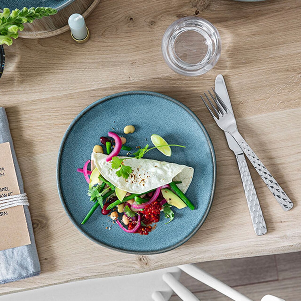 Ontbijtbord Lave 23,5 cm in turkoois, van bovenaf gefotografeerd, met een decoratief gerecht van groenten en een omelet, opgesteld op een houten tafel.