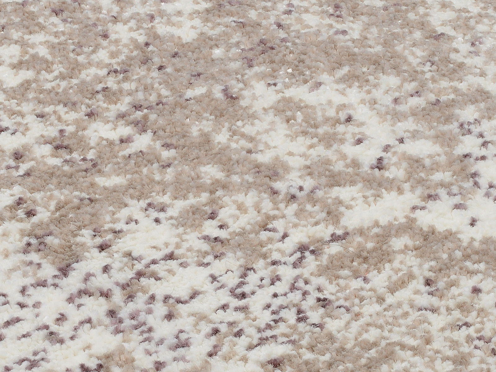 Nahaufnahme eines Designer Teppichs mit einem gemusterten, flauschigen Textur in Beige- und Weißtönen.