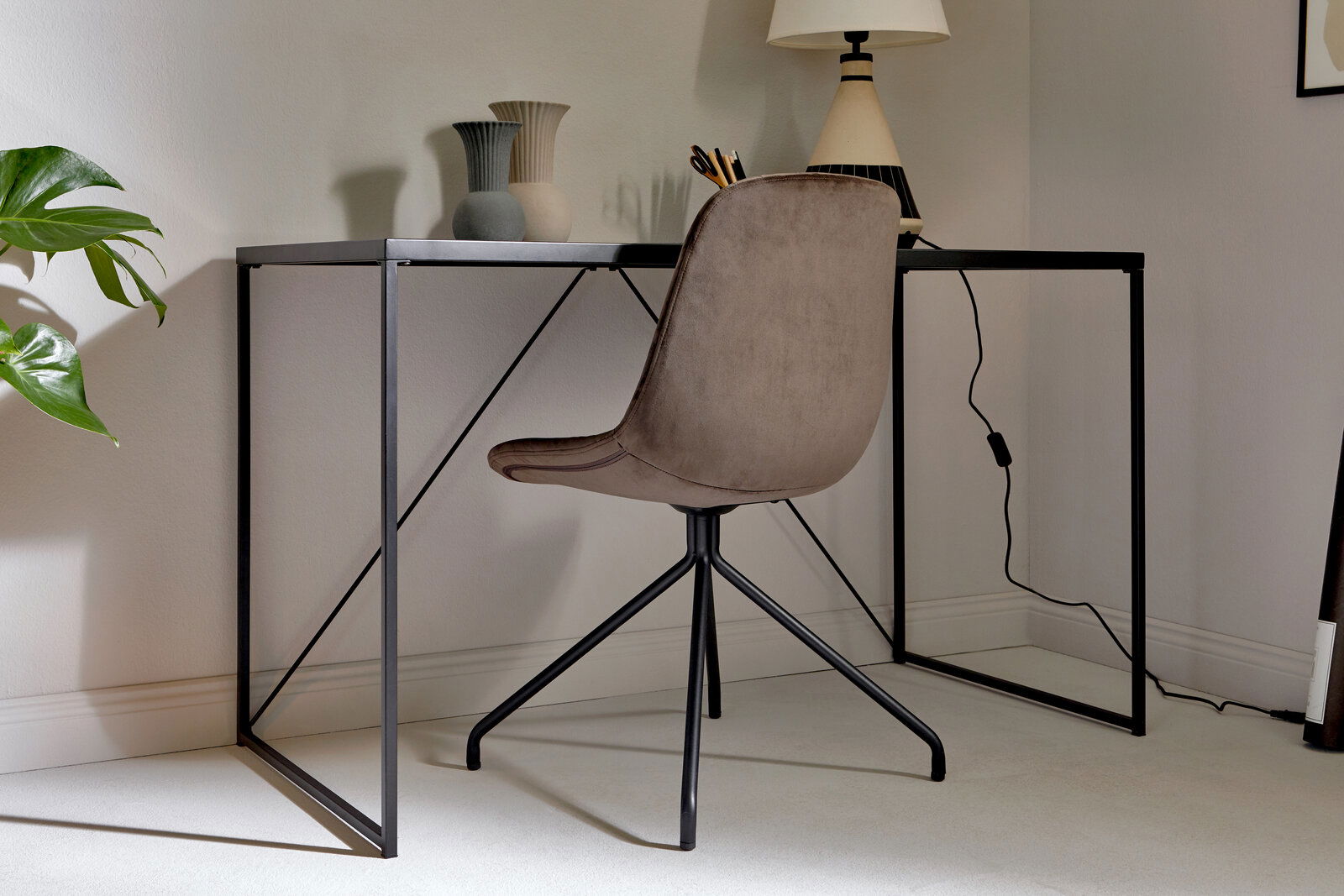 Moderner Schreibtisch mit schwarzem Metallrahmen und dekorativen Vasen, seitliche Perspektive