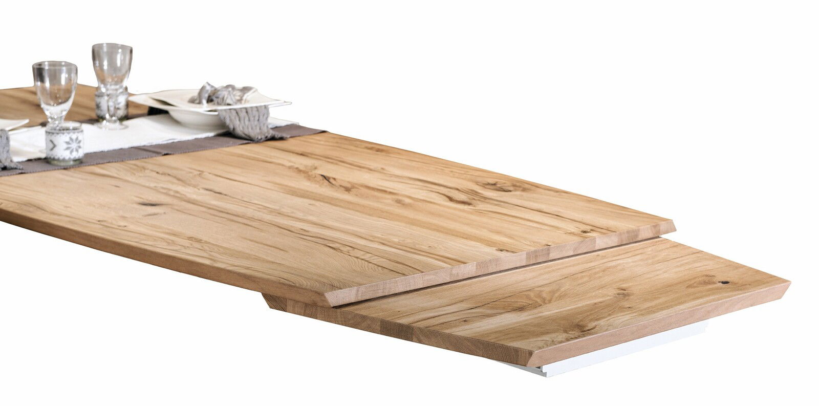 Nahaufnahme eines Voglauer Esstisches V-ROCK aus Holz mit natürlicher Maserung, gedeckt mit Geschirr und Gläsern, seitliche Perspektive.