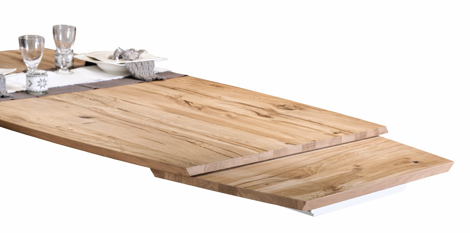 Nahaufnahme eines Voglauer Esstisches V-ROCK aus Holz mit natürlicher Maserung, gedeckt mit Geschirr und Gläsern, seitliche Perspektive.