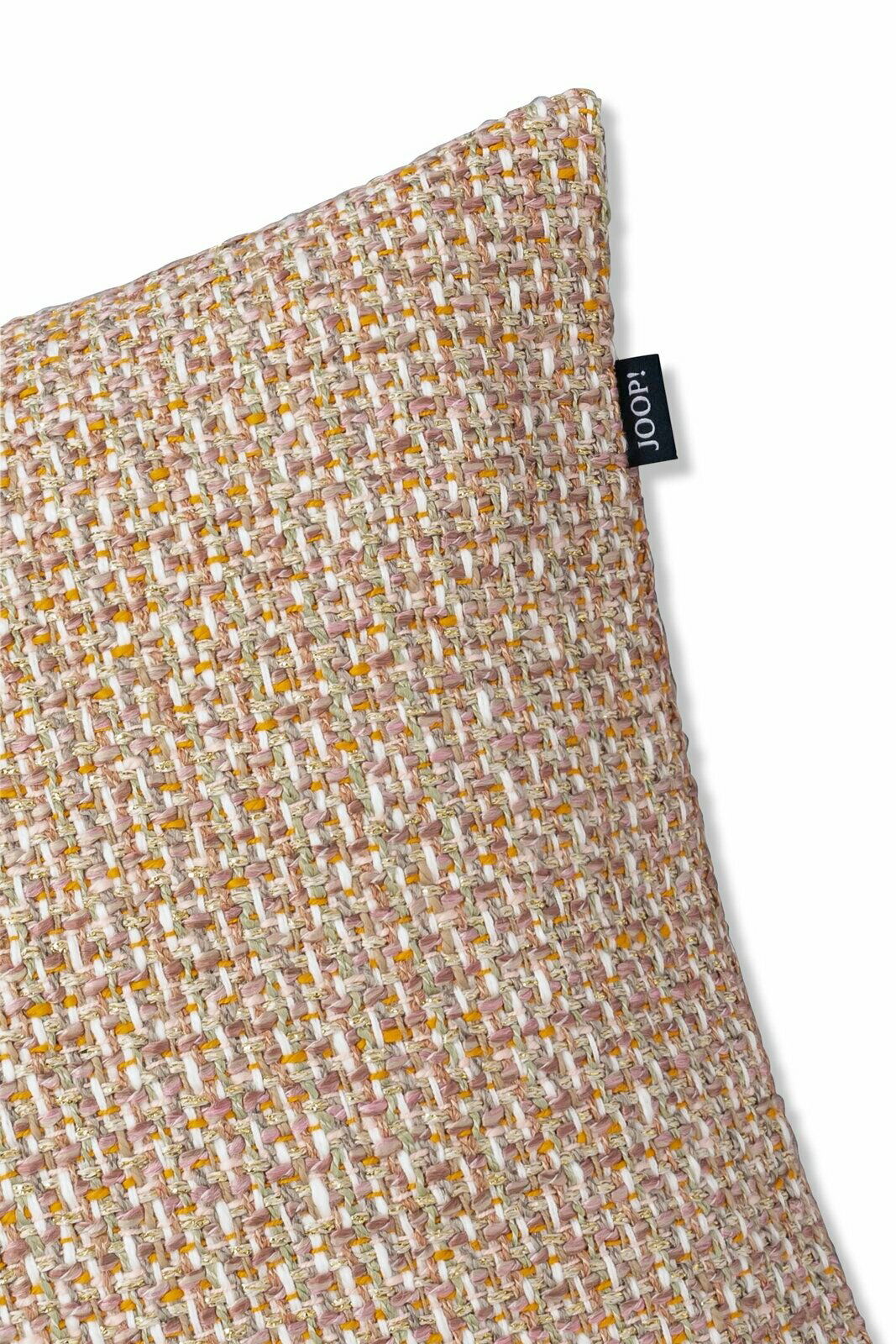 Nahaufnahme einer strukturierten Zierkissenhülle in beige und braun mit einem kleinen schwarzen Etikett an der Seite, perspektivisch von oben fotografiert.