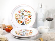 Pizza-Teller-Set aus weißem Porzellan mit rotem Rand und farbigem Pizza-Motiv (Schriftzug „PIZZA“, Pizzastücke, Koch, Tomaten und Oliven), in schräger Frontansicht auf gedecktem Küchentisch; ein Teller steht im Hintergrund, mehrere liegen gestapelt im Vor