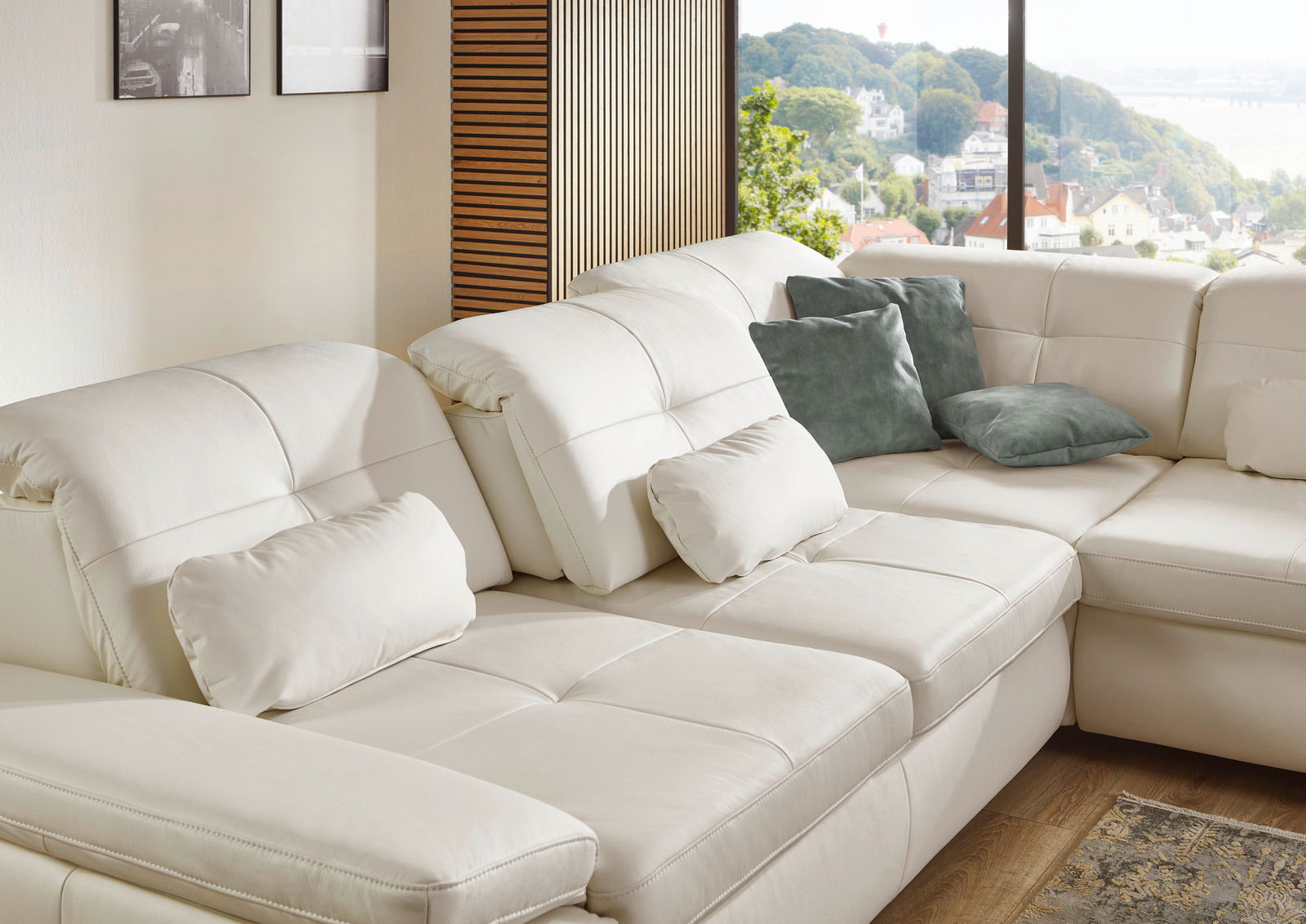 Eckgarnitur in cremefarbenem Leder mit mehreren Kissen, seitliche Perspektive