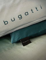 Nahaufnahme von Bettwäsche mit dem Schriftzug 'bugatti' in grünen Tönen.