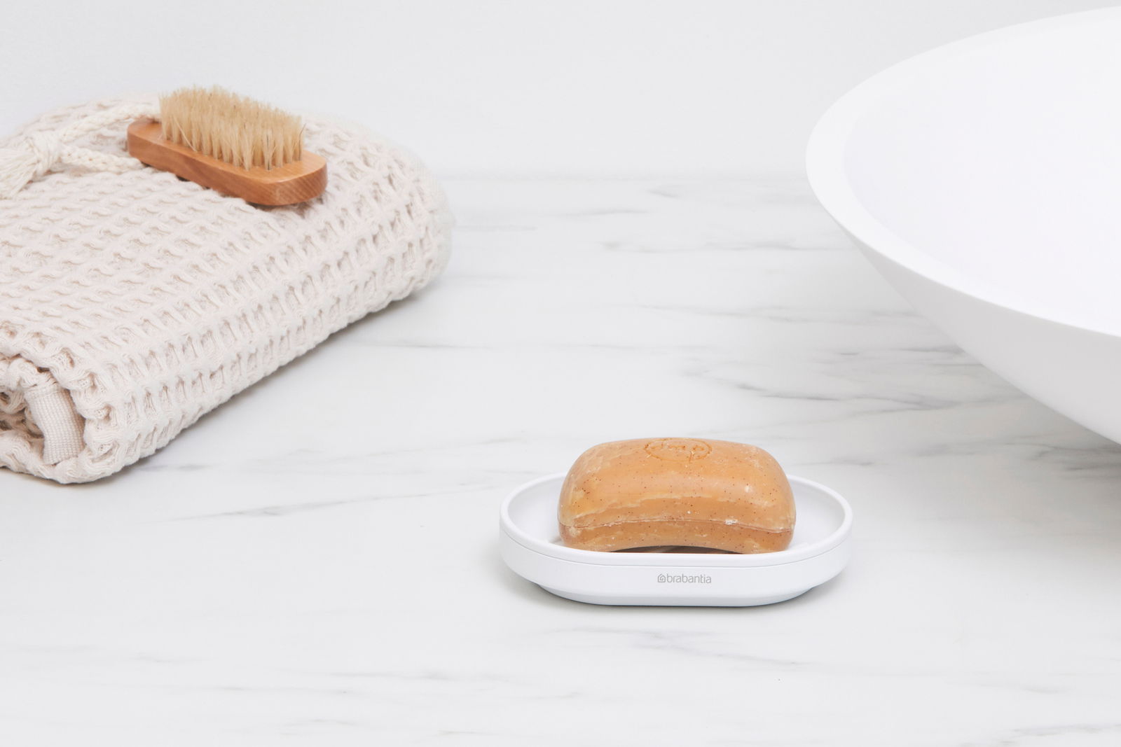 Brabantia Zeepbakje MINDSET Seifenschale mit Seife, seitliche Perspektive, auf einem Marmorwaschtisch neben einem gefalteten Handtuch und einer Bürste