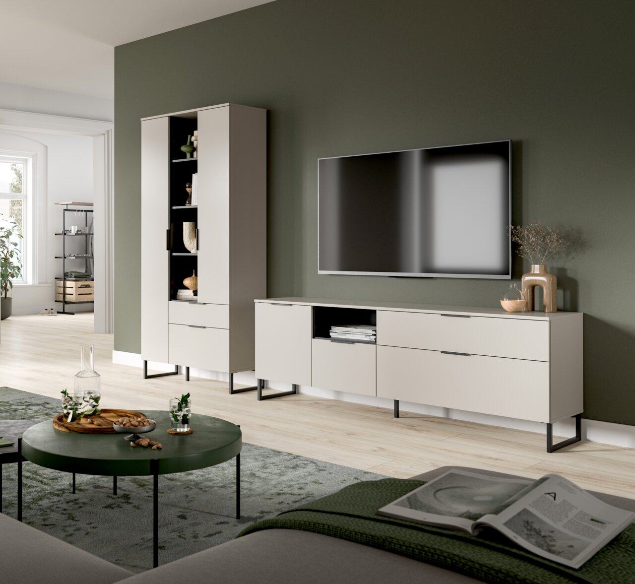 MID.YOU Wohnkombination NOIDA Modernes Wohnzimmer-Setup mit hellbeigem TV-Lowboard und passendem Hochschrank auf schwarzen Metallfüßen, wandmontiertem Fernseher und Deko vor olivgrüner Wand, perspektivisch in leichter Schrägansicht von vorn.