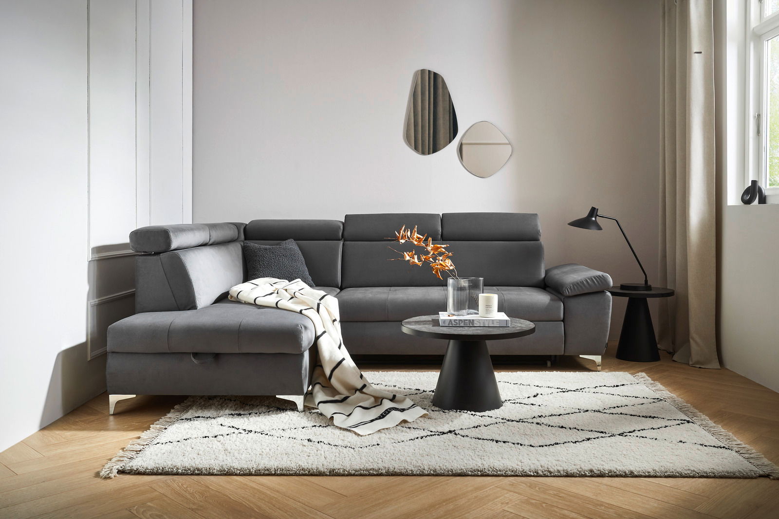 Graue Rundecke Osca in modernem Wohnzimmer, seitliche Perspektive, mit Kissen und Decke dekoriert, auf hellem Teppich.