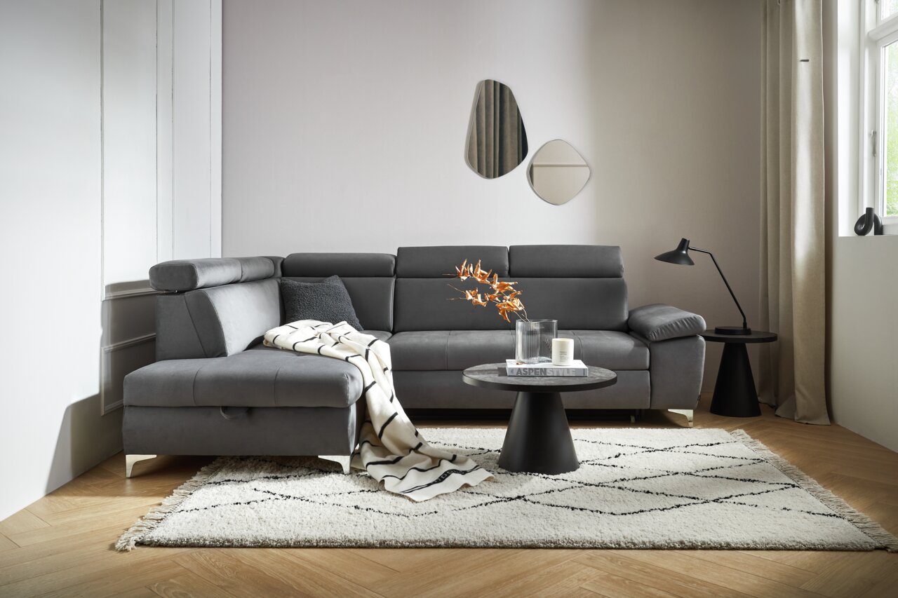 Graue Rundecke Osca in modernem Wohnzimmer, seitliche Perspektive, mit Kissen und Decke dekoriert, auf hellem Teppich.