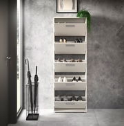 Schuhkipper mit fünf Fächern, frontal fotografiert, gefüllt mit verschiedenen Schuhen, in einem modernen Raum mit grauer Wand und Regenschirmständer.