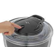 Nahaufnahme einer Salatschleuder TURBO mit einer Hand, die den Knopf auf dem Deckel drückt.