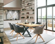 Moderner Esstisch mit Holzplatte und Metallbeinen, umgeben von grauen Stühlen in einem hellen, stilvollen Esszimmer mit Blick auf große Fenster.