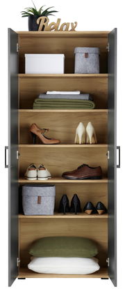 Vorderansicht eines XL-Schuhschranks mit offenen Türen, gefüllt mit Schuhen, Körben und Kissen, dekoriert mit einer Pflanze und einem 'Relax'-Schriftzug oben.