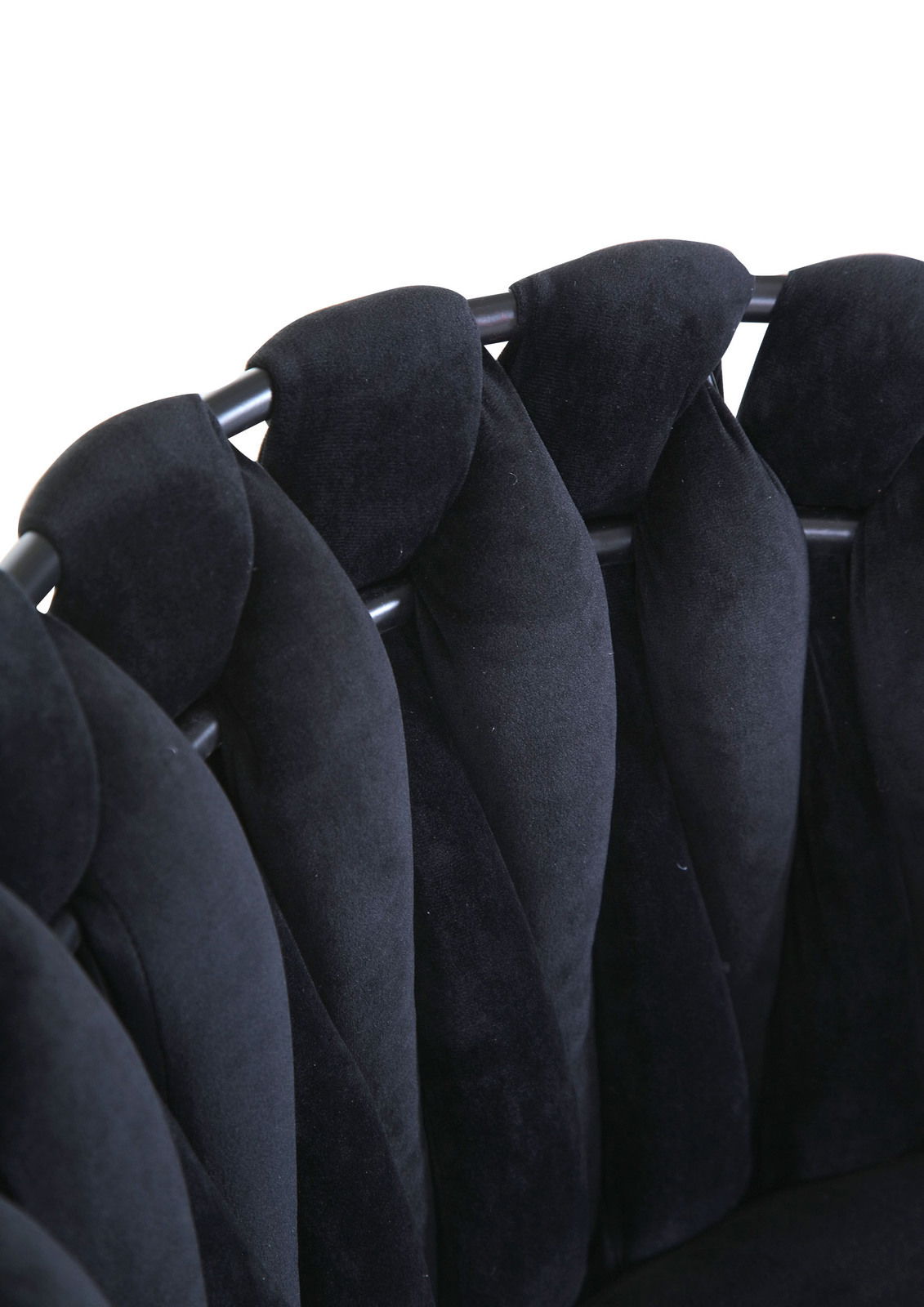 Nahaufnahme eines schwarzen Sessels mit gepolsterten, geflochtenen Elementen und Metallrahmen, von oben betrachtet.